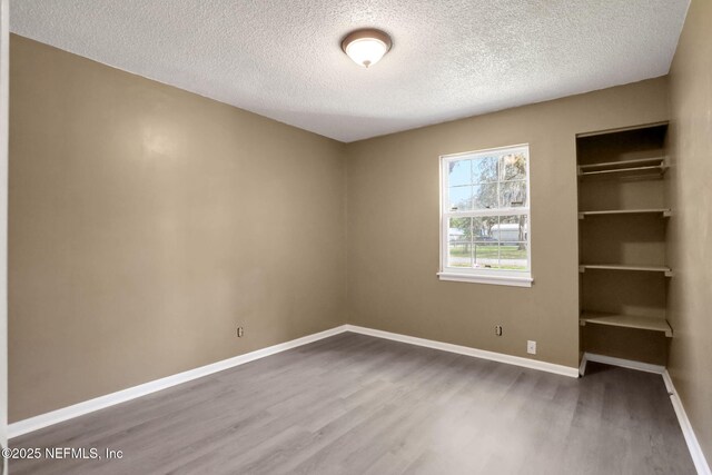 4245 New Hampshire Rd, Elkton, FL 32033 - unfurnished bedroom with a textured ceiling, baseboards, and wood finished floors