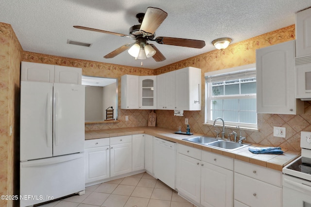 4245 New Hampshire Rd, Elkton, FL 32033 - kitchen with a sink, tile counters, white appliances, white cabinets, and ceiling fan