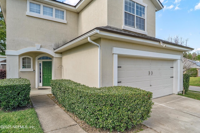 property entrance featuring stucco siding, a garage, and concrete driveway