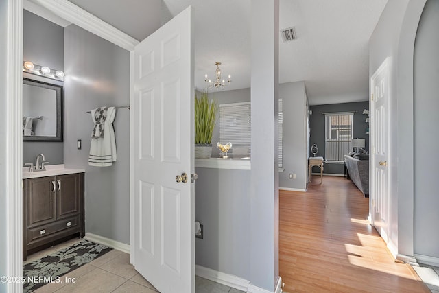 bathroom featuring vanity, a chandelier, wood finished floors, baseboards, and visible vents