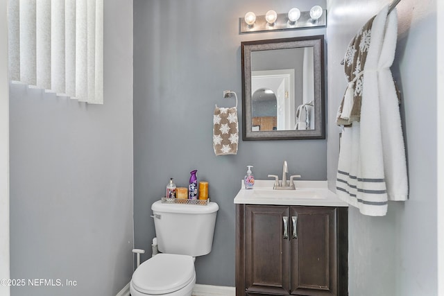 half bath featuring toilet, vanity, and baseboards