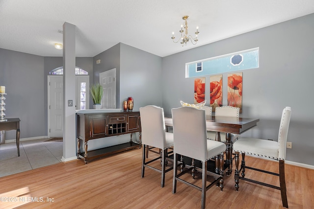 dining space with baseboards, light wood-style flooring, and an inviting chandelier