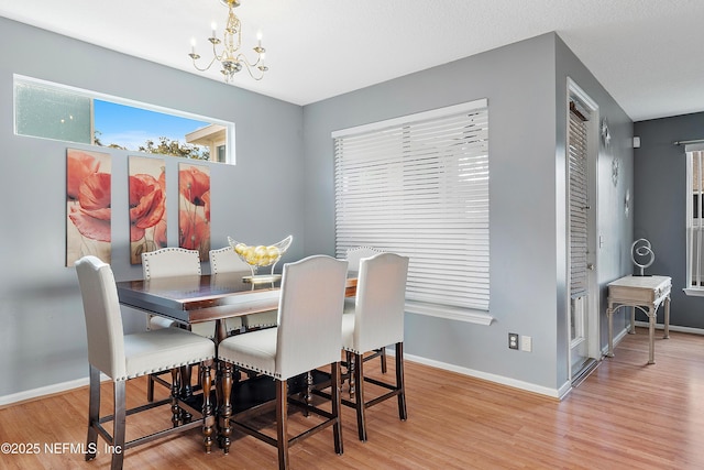 dining space featuring baseboards, a notable chandelier, and light wood-type flooring