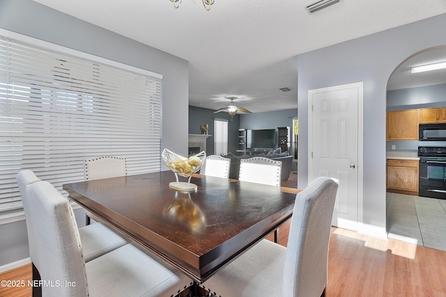 dining space featuring arched walkways, ceiling fan, visible vents, and light wood-type flooring