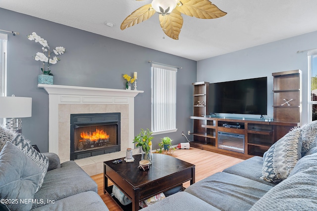 living room with a wealth of natural light, a fireplace, wood finished floors, and ceiling fan