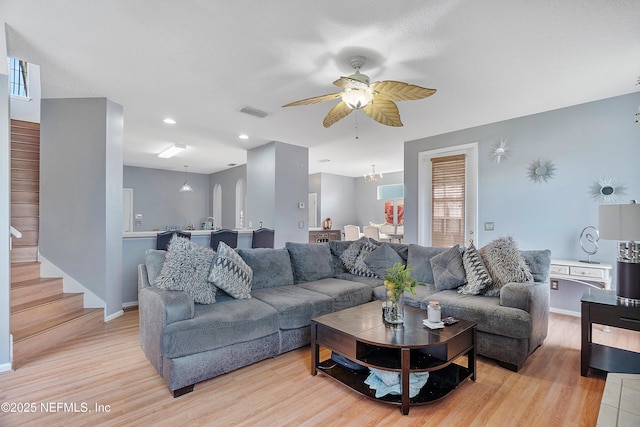 living area featuring baseboards, visible vents, light wood-style floors, and a ceiling fan