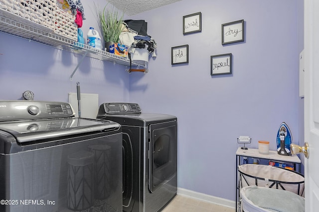 washroom with baseboards, separate washer and dryer, and laundry area