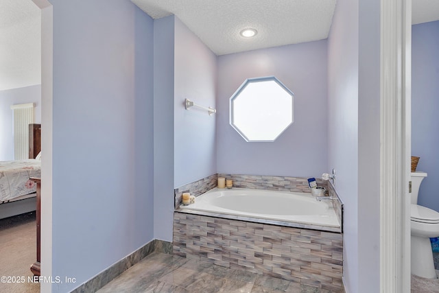 ensuite bathroom with a bath, toilet, ensuite bathroom, and a textured ceiling