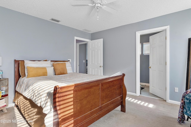 bedroom featuring light colored carpet, baseboards, a textured ceiling, ceiling fan, and visible vents