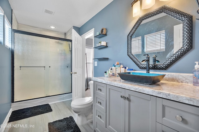 full bathroom featuring a stall shower, visible vents, toilet, and vanity