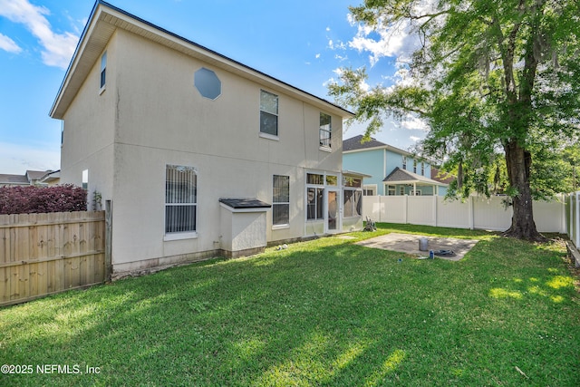 rear view of property featuring a lawn, a fenced backyard, and stucco siding