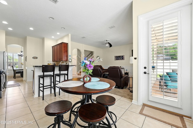 dining room featuring arched walkways, light tile patterned floors, recessed lighting, and a chandelier