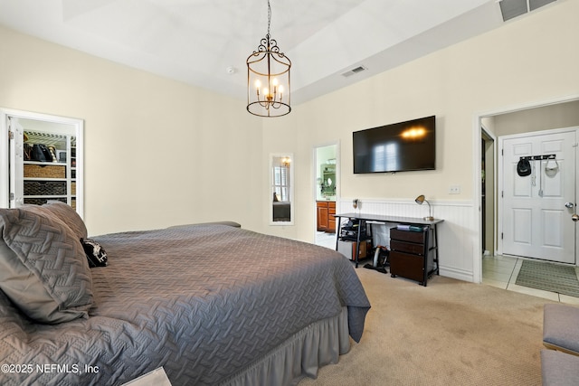 bedroom with a chandelier, light carpet, and a wainscoted wall