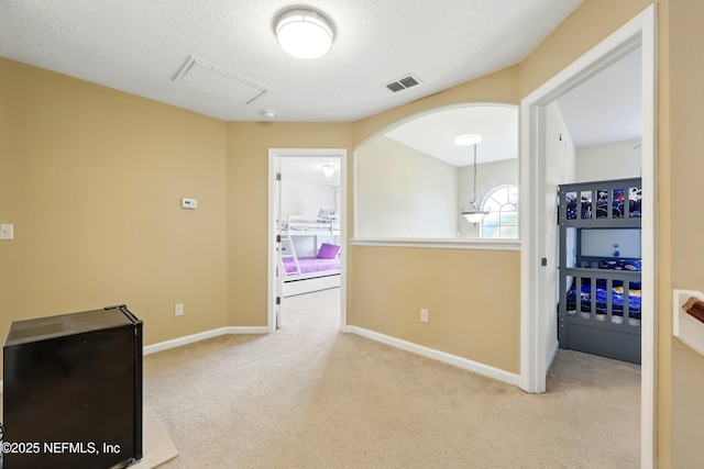 hallway featuring carpet flooring, baseboards, and a textured ceiling