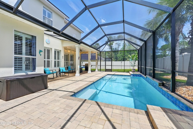 view of pool featuring a patio, glass enclosure, and a fenced backyard