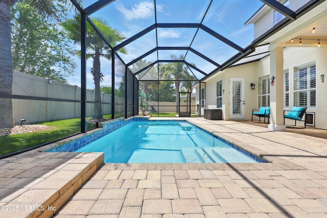 view of pool with a patio area, glass enclosure, and a fenced backyard