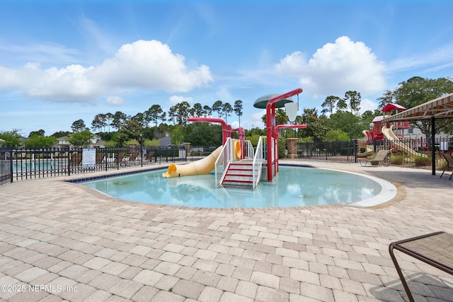 community pool featuring a water play area, a water slide, and a patio area