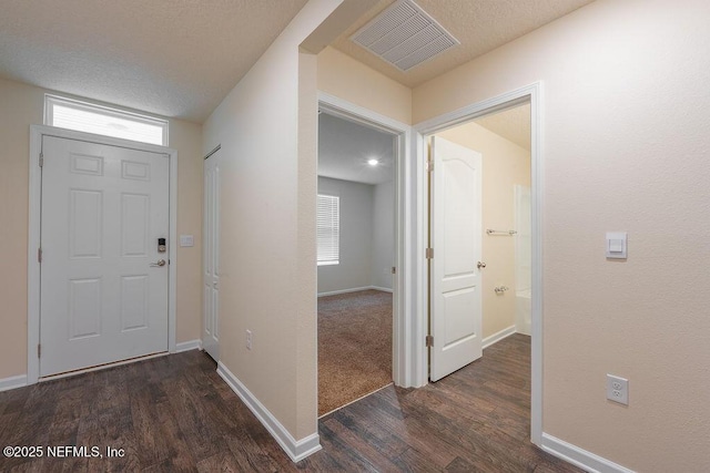 foyer featuring baseboards, visible vents, wood finished floors, and a textured ceiling