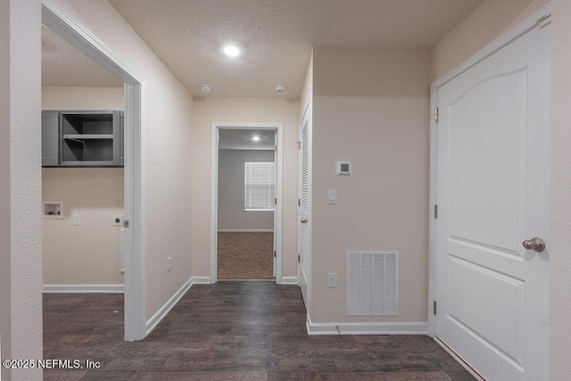 hallway featuring baseboards, visible vents, wood finished floors, and a textured ceiling