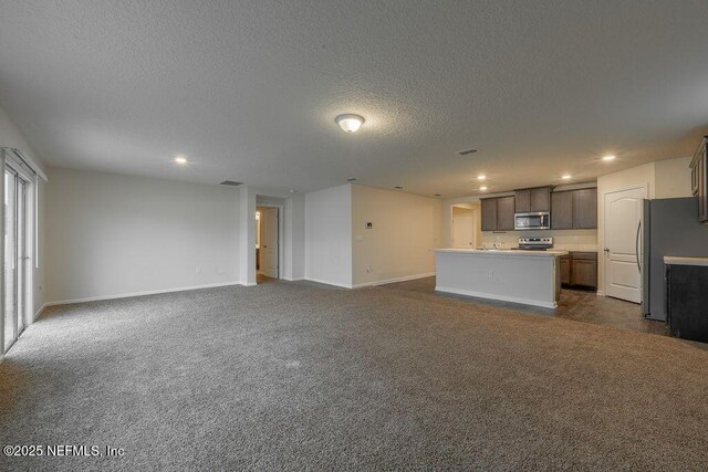 unfurnished living room featuring a textured ceiling, visible vents, baseboards, recessed lighting, and dark carpet