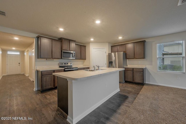 kitchen featuring light countertops, a sink, appliances with stainless steel finishes, and dark wood-type flooring