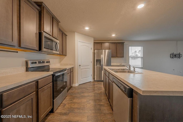 kitchen featuring light countertops, dark wood-style flooring, a sink, and appliances with stainless steel finishes