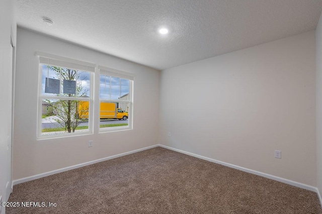 carpeted empty room featuring baseboards and a textured ceiling