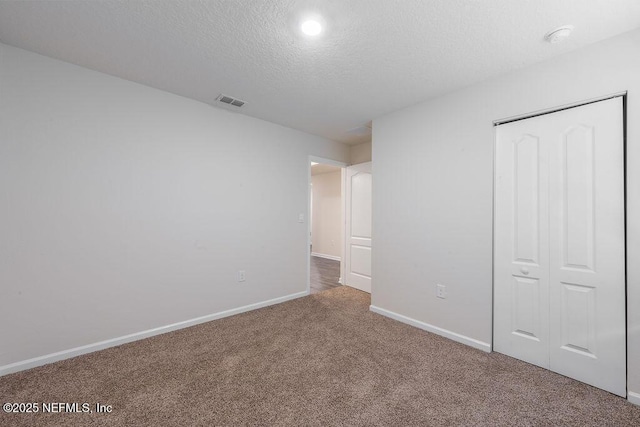 unfurnished bedroom with a closet, a textured ceiling, baseboards, visible vents, and carpet