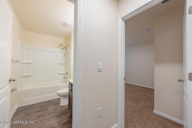 bathroom with shower / bathing tub combination, vanity, baseboards, a textured ceiling, and wood finished floors