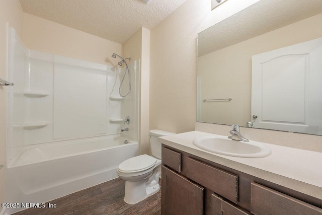 bathroom featuring a textured ceiling, wood finished floors, toilet, vanity, and shower / washtub combination