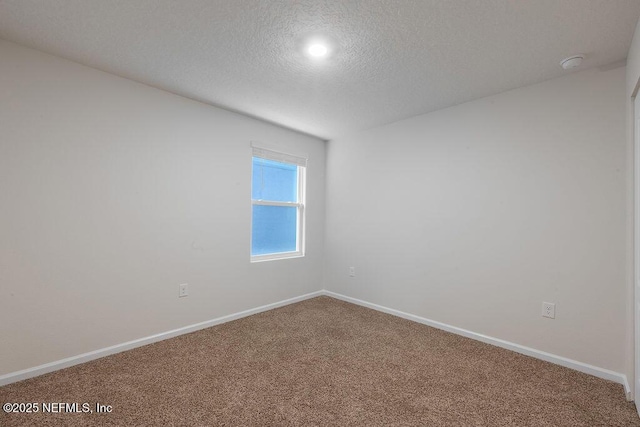 carpeted spare room featuring baseboards and a textured ceiling
