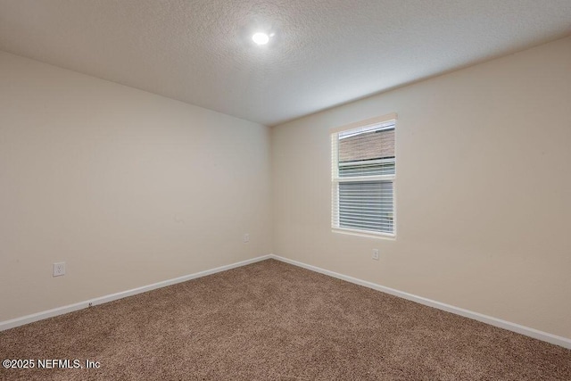 spare room featuring carpet flooring, baseboards, and a textured ceiling