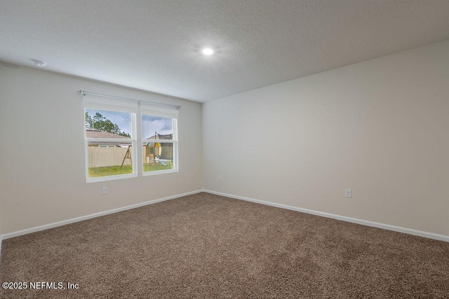 spare room with baseboards, a textured ceiling, and carpet