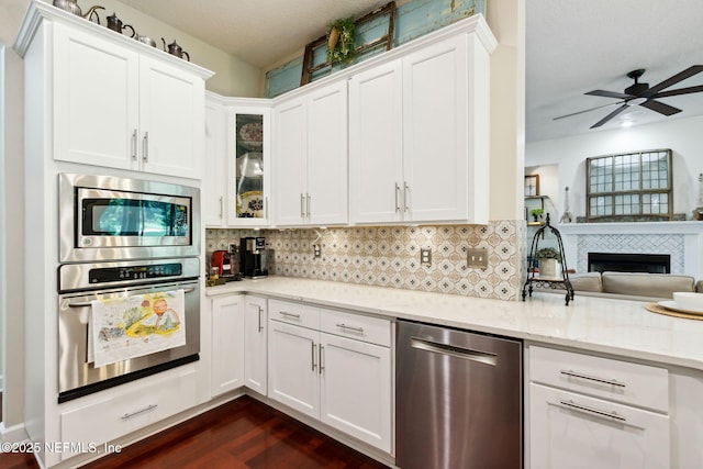 95150 Starling Ct, Fernandina Beach, FL 32034 - kitchen featuring appliances with stainless steel finishes, white cabinetry, light stone counters, and glass insert cabinets