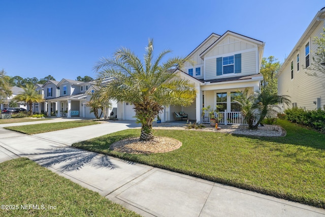 view of front of house featuring a garage, a front lawn, board and batten siding, driveway, and a porch