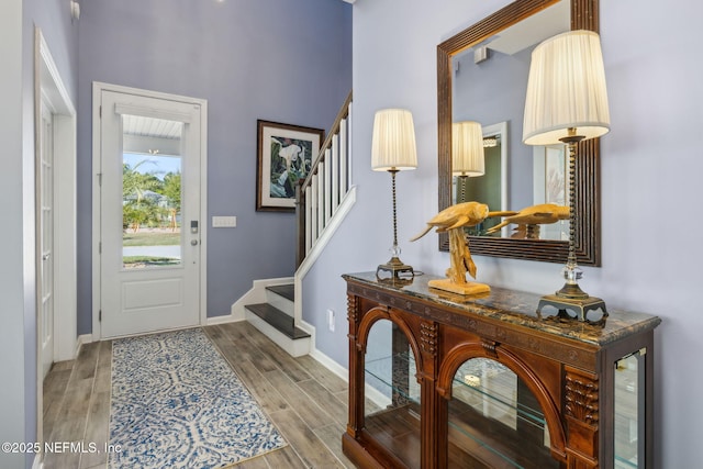 entrance foyer featuring baseboards, wood finished floors, and stairway