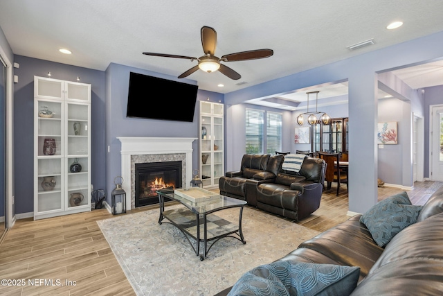 living area featuring a ceiling fan, a glass covered fireplace, wood finish floors, baseboards, and recessed lighting