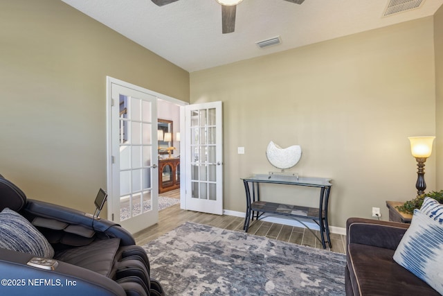 living area with visible vents, wood finished floors, french doors, and a ceiling fan