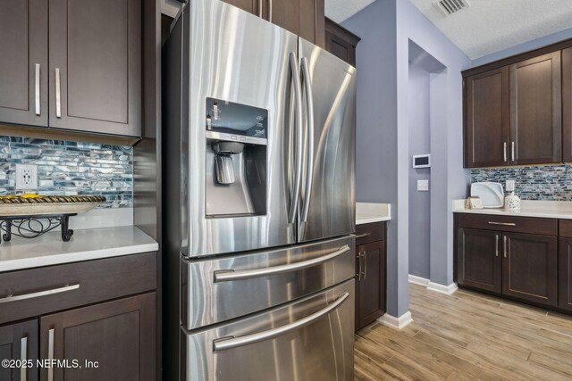 kitchen with light countertops, dark brown cabinetry, and stainless steel fridge