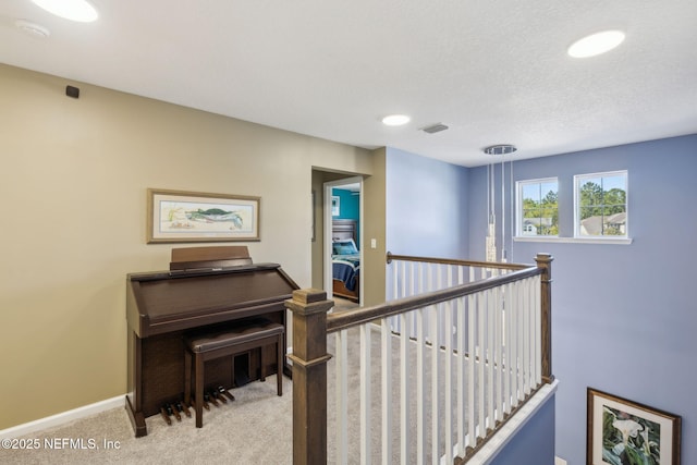 staircase featuring carpet flooring, a textured ceiling, baseboards, and visible vents