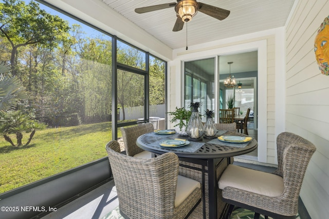 sunroom / solarium featuring ceiling fan with notable chandelier and outdoor dining space