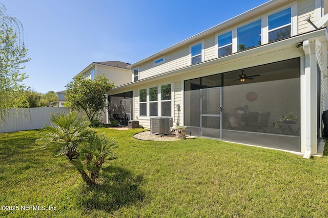 rear view of house with a lawn, cooling unit, a sunroom, and fence