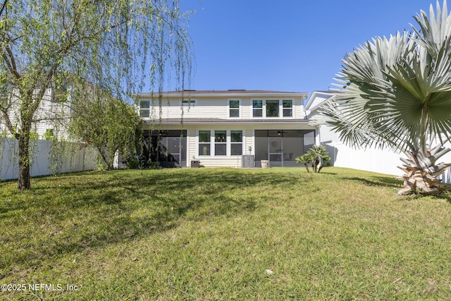 rear view of property with a sunroom, fence, and a yard