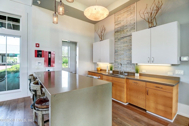 kitchen with a breakfast bar area, a center island, dark wood-type flooring, a sink, and a towering ceiling