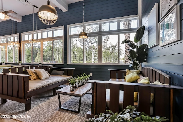 sunroom / solarium with a wealth of natural light, wooden walls, and beam ceiling