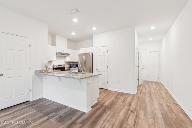 7686 Merchants Way, Jacksonville, FL 32222 - kitchen featuring light wood-style flooring, visible vents, a peninsula, stainless steel appliances, and light stone counters