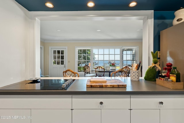 1301 Redbud Ln, Jacksonville, FL 32207 - kitchen with dark countertops, black electric stovetop, white cabinets, ornamental molding, and recessed lighting