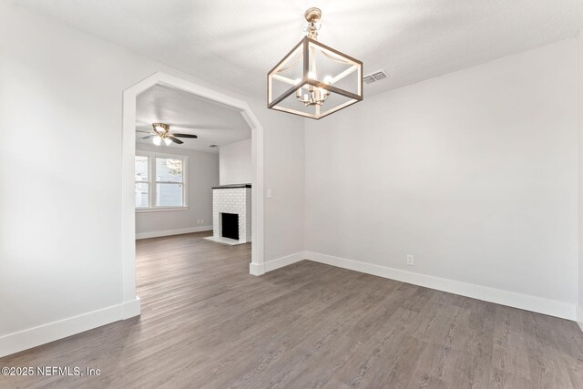 4651 Polaris St, Jacksonville, FL 32205 - unfurnished living room with visible vents, baseboards, a fireplace, wood finished floors, and ceiling fan with notable chandelier