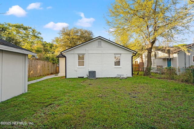 4651 Polaris St, Jacksonville, FL 32205 - back of house featuring a lawn, brick siding, fence, and central AC unit