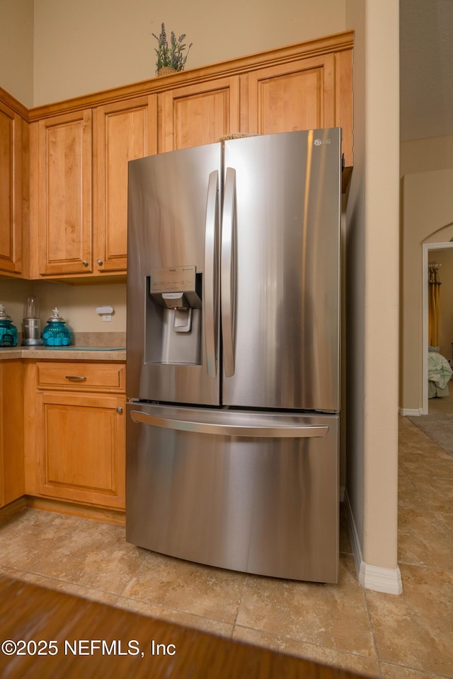 784 Crestwood Dr, Saint Augustine, FL 32086 - kitchen with light countertops, baseboards, arched walkways, stainless steel refrigerator with ice dispenser, and brown cabinetry